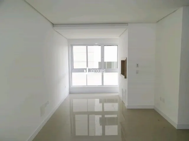 Interior de um ambiente claro com paredes brancas e piso reflexivo.