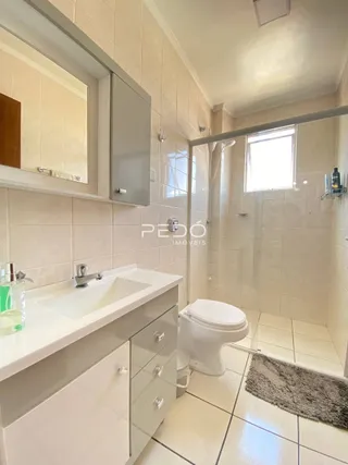 Banheiro com piso de cerâmica e box de vidro.
