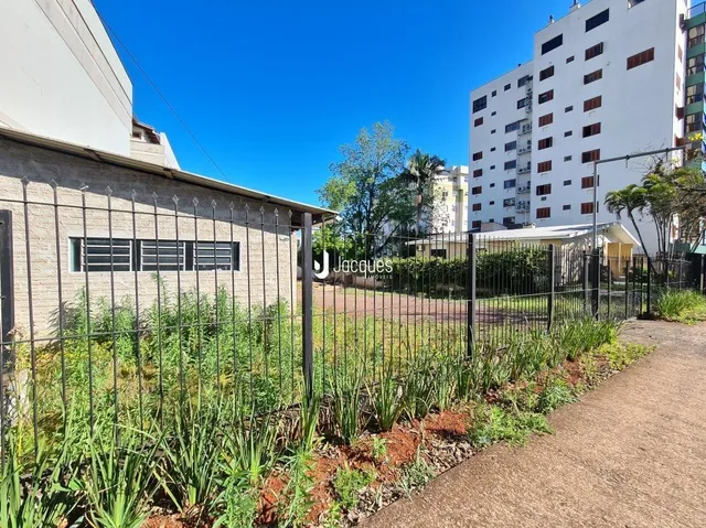 Fachada de uma propriedade com cerca e vegetação no jardim.