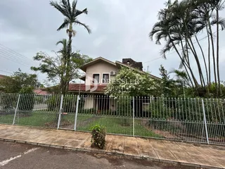 Fachada de uma residência com cerca de metal e vegetação em Lajeado, Brasil.