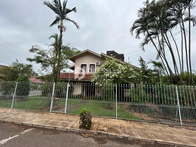 Fachada de uma residência com cerca de metal e vegetação em Lajeado, Brasil.