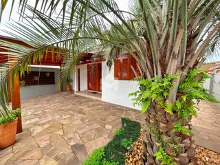Área externa pavimentada com piso de pedra e vegetação exuberante.