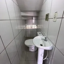 Foto de um corredor com paredes de azulejo branco e uma pia.