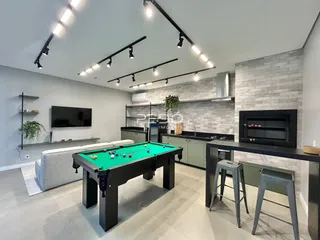 Sala de estar moderna com mesa de bilhar e cozinha integrada.