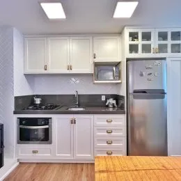 Cozinha com armários brancos e bancada escura.