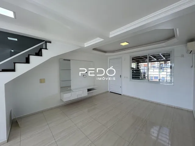 Vista interna de um ambiente com piso claro e escadaria em um imóvel.
