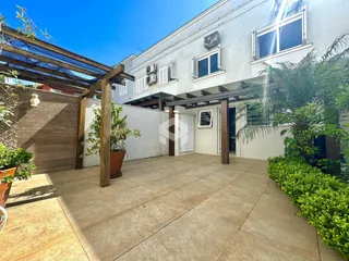 Vista da fachada de uma residência com área externa e pergolado.