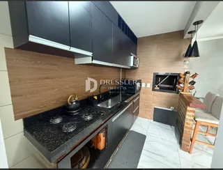 A cozinha apresenta armários escuros e bancada preta com piso de porcelanato claro.