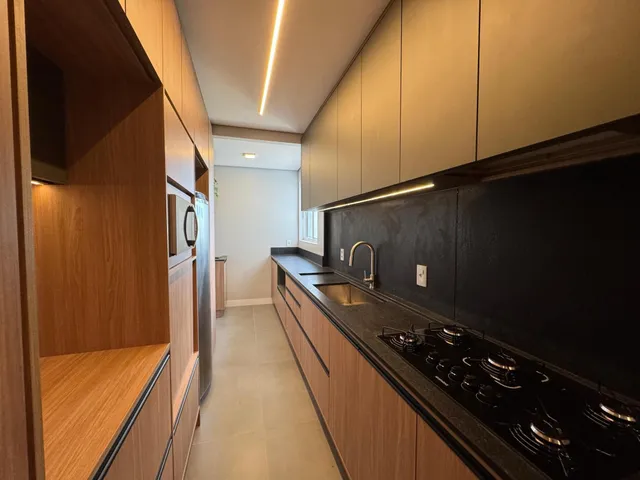 Cozinha moderna com armários de madeira e bancada escura.