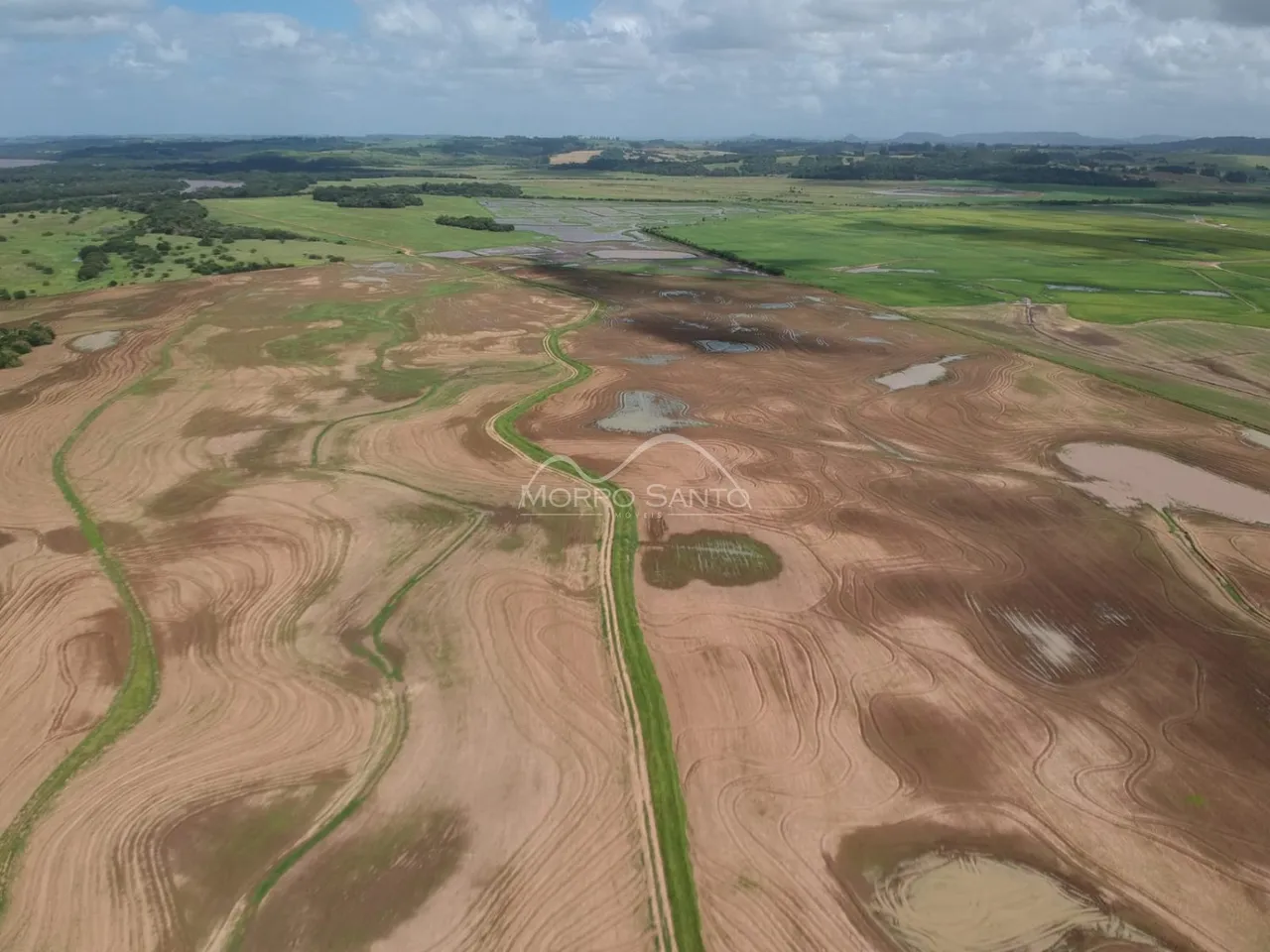 Vista aérea de uma área de terra rural com campos secos e trilhas.
