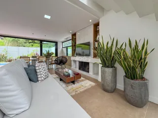 Sala de estar moderna com sofá branco e decoração de plantas.