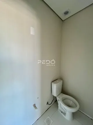 Vista interna de um corredor com porta e vaso sanitário.