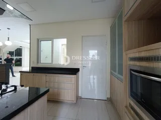 Vista interna de uma cozinha moderna com armários de madeira e bancada escura.