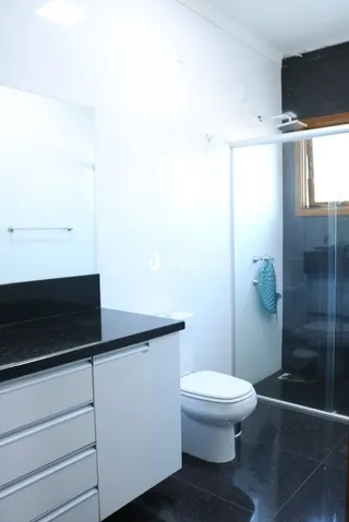 Foto do interior de um banheiro com piso escuro e vaso sanitário branco.