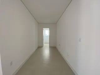 Foto de um corredor interno com paredes brancas e piso claro.
