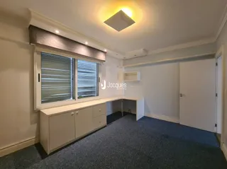 Ambiente interno de uma sala com janelas e armários em madeira.