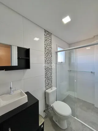 Foto interna de um banheiro com revestimento de azulejos brancos e cinzas.