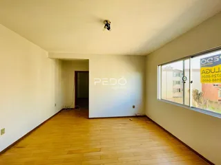 Corredor com piso de madeira e janela na parede direita.