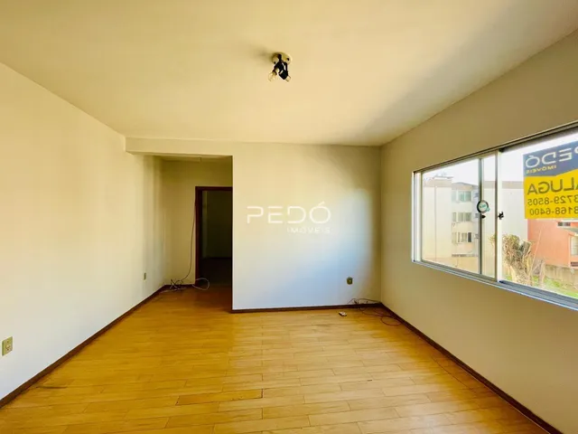 Corredor com piso de madeira e janela na parede direita.
