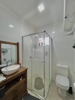 Interior de um banheiro com box de vidro e vaso sanitário branco.