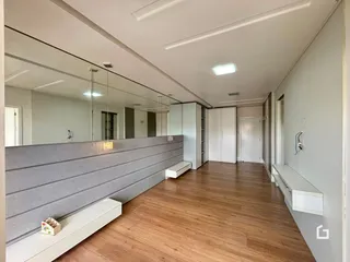 Hall de corredor com piso de madeira e paredes cinzas.
