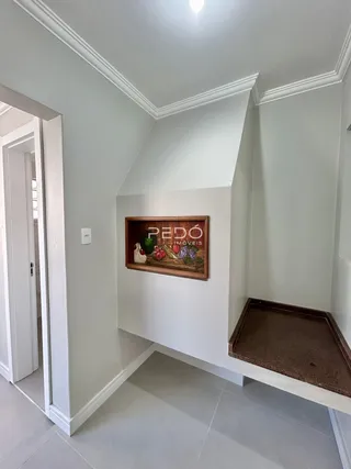 Hall de entrada com parede branca e molduras na residência.