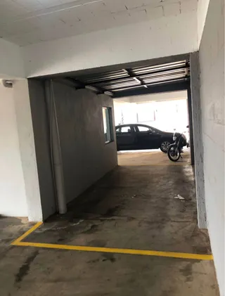 Foto de um corredor ou área de acesso com piso de concreto e abertura para o exterior.