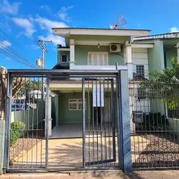 Fachada de uma residência com portão de metal e cerca.