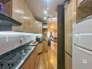 Cozinha moderna com armários de madeira e bancada escura.