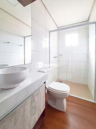 Banheiro com bancada de mármore e box de vidro transparente.