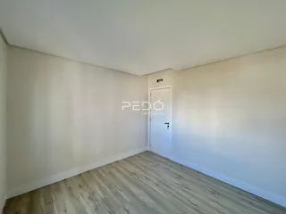 Ambiente interno de uma sala com piso de madeira clara e paredes brancas.