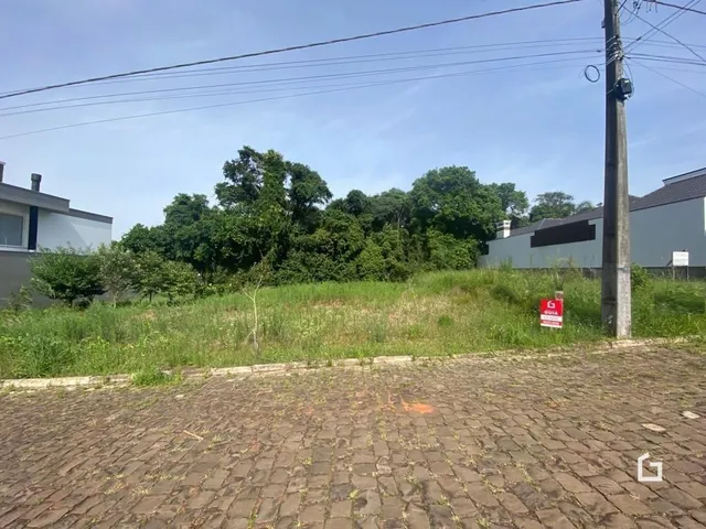 Vista externa da propriedade com grama alta e pavimentação de tijolos.