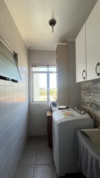 Corredor interno com revestimento cerâmico e armários brancos.