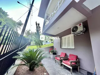 Vista da área externa com móveis de madeira e vegetação em um apartamento.
