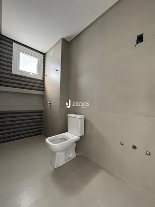 Foto de um banheiro interno com piso de cerâmica e vaso sanitário branco.
