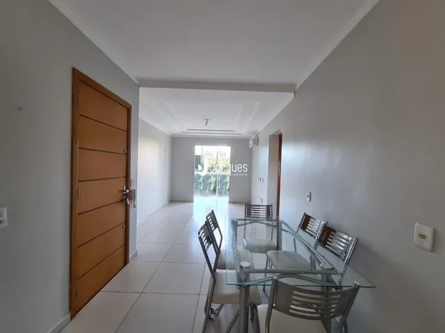 Hall de entrada com porta de madeira e piso cerâmico claro.