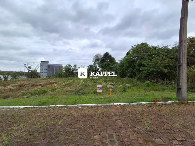 Vista externa de uma propriedade com vegetação e um prédio ao fundo.
