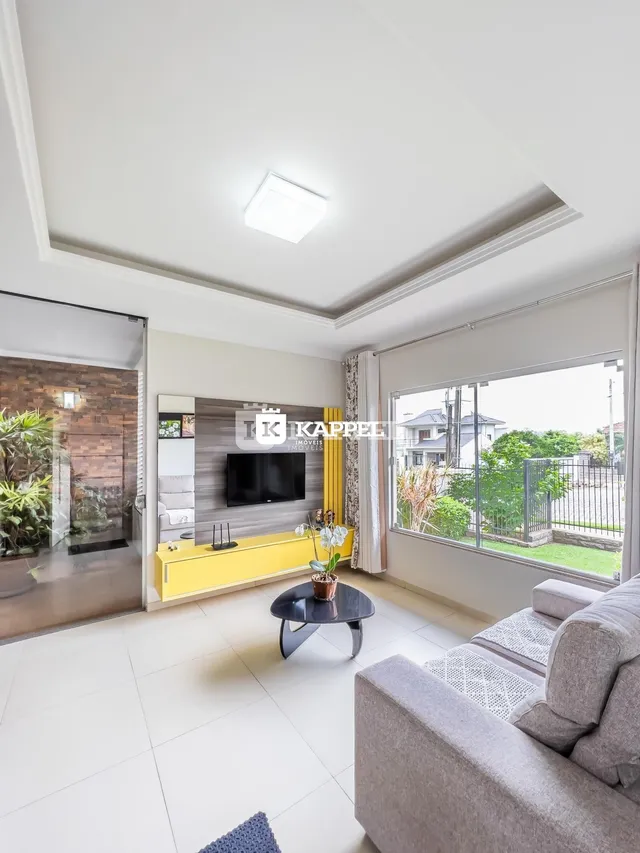 Sala de estar moderna com sofá e televisão em um apartamento em Lajeado.