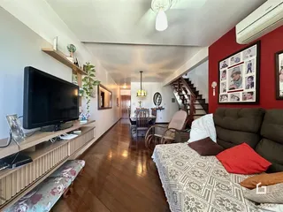 Interior de uma sala de estar com vista para um corredor e escadaria em uma residência.
