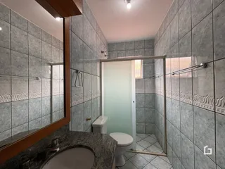 Foto de um banheiro com revestimento de azulejos cinzas e divisória de vidro.