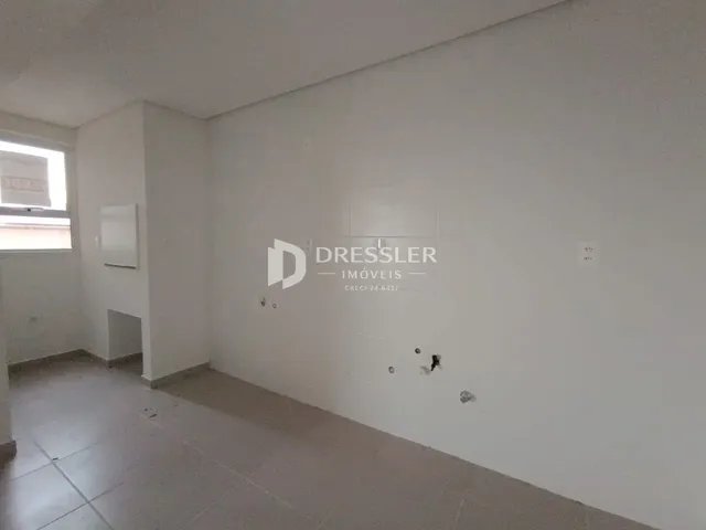Vista de um corredor interno com paredes brancas e piso claro.
