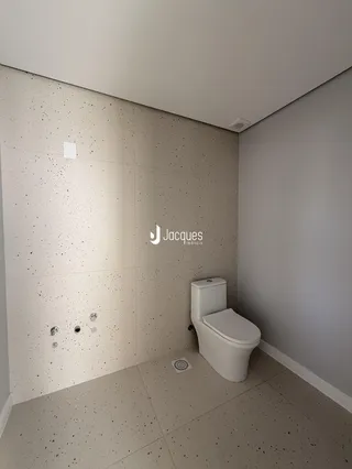 A foto mostra o interior de um banheiro com revestimento de parede e piso claros.