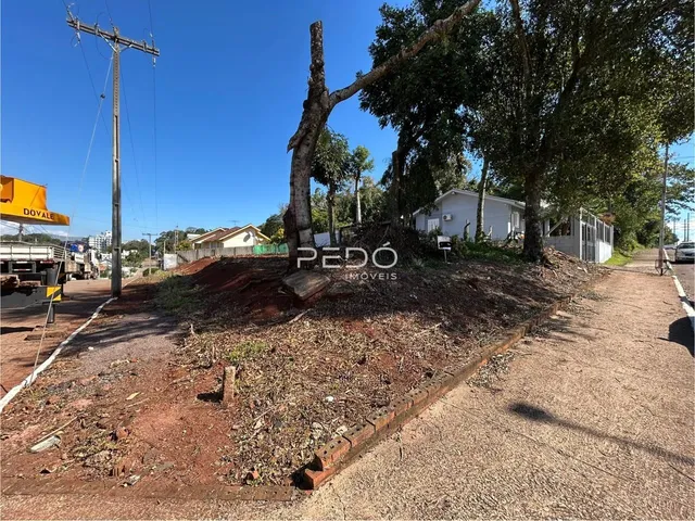 Vista externa de uma propriedade com terreno e vegetação ao redor.