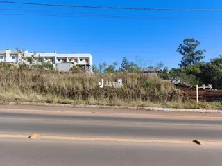 Vista externa de uma propriedade com vegetação seca e uma estrada no primeiro plano.