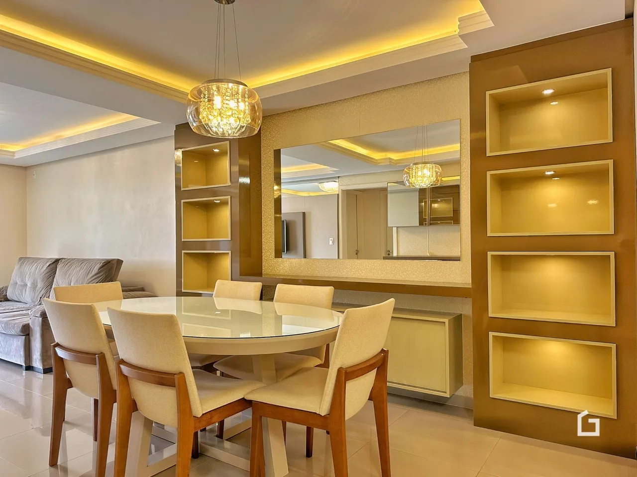 Ambiente interno de sala de jantar com mesa de vidro e decoração de parede em Lajeado.