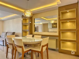 Ambiente interno de sala de jantar com mesa de vidro e decoração de parede em Lajeado.