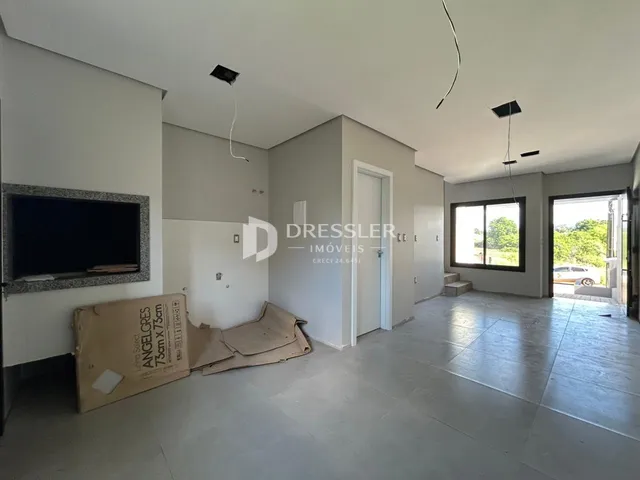 Sala de estar com piso de cerâmica e paredes brancas em um imóvel.