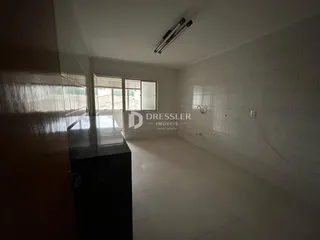 Um corredor interno com piso de cerâmica e paredes brancas.