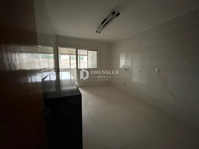 Um corredor interno com piso de cerâmica e paredes brancas.
