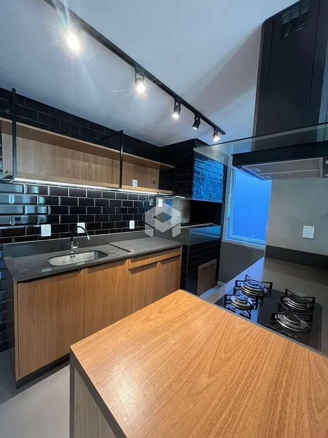 Cozinha moderna com armários de madeira e revestimento preto.